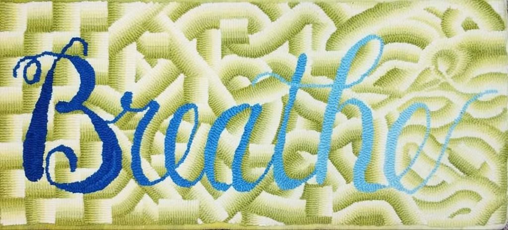 Hooked rug with the word Breathe on it.